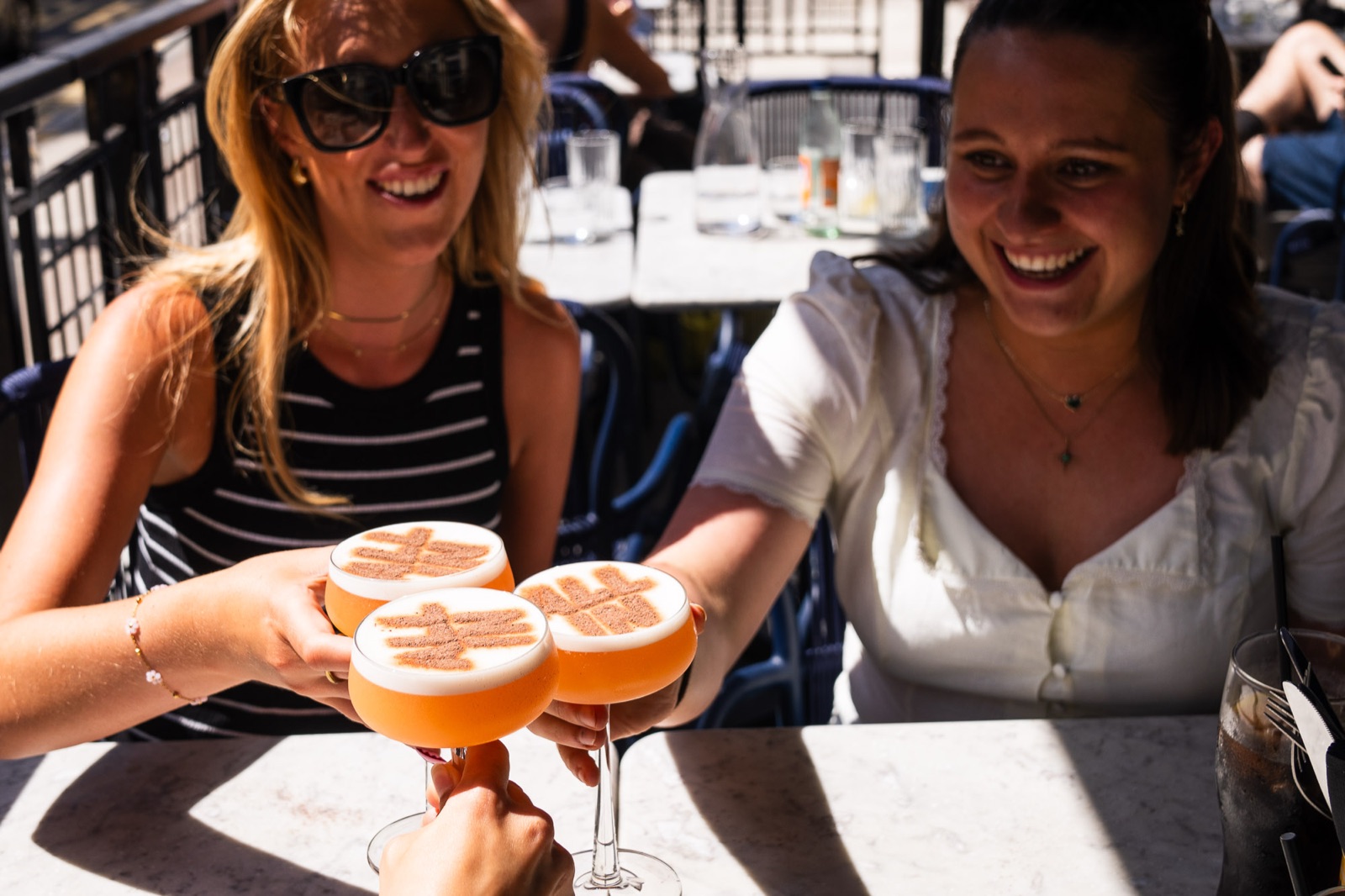 Friends toasting with All In stencilled cocktails at a Glasgow venue