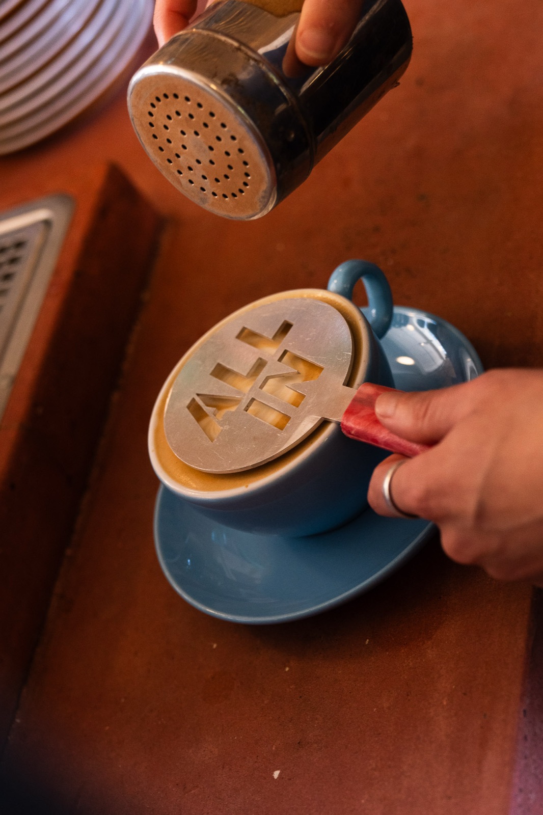 An All In stencil used to create the mark on a coffee at a venue
